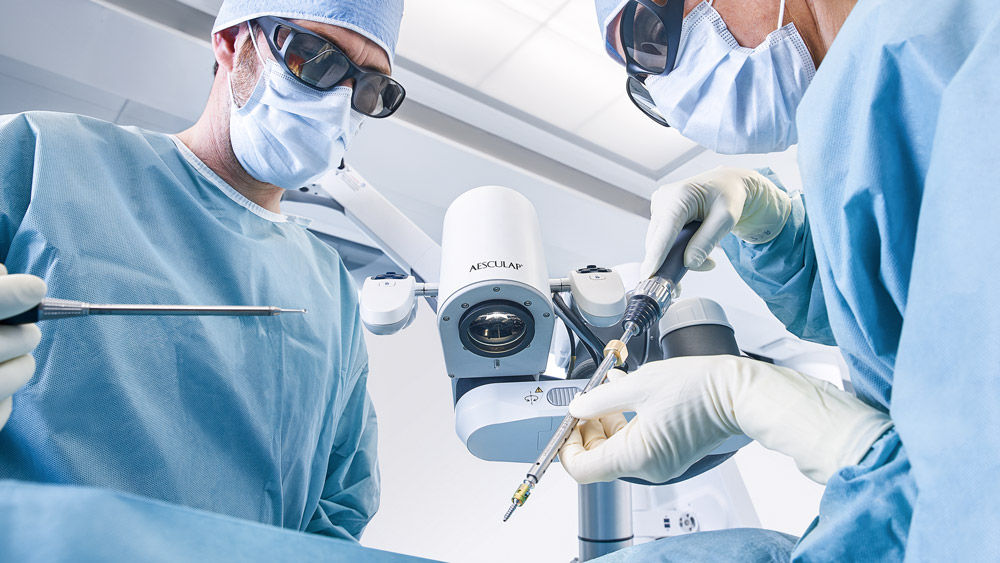 Dos cirujanos en el quirófano utilizando un microscopio digital durante un procedimiento quirúrgico