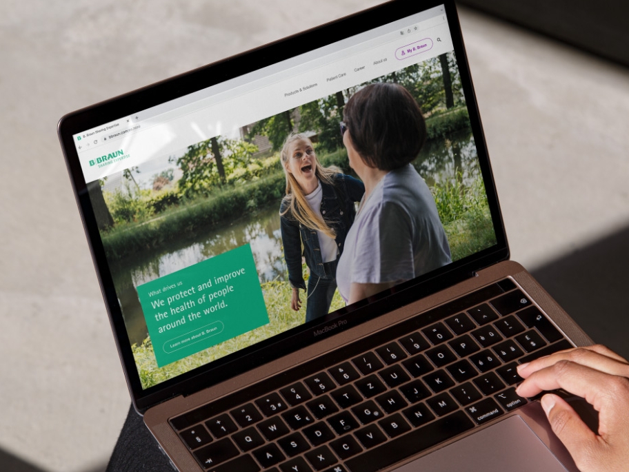 Un ordenador portátil con el sitio web de B. Braun abierto y una mano apoyada en la parte inferior derecha del ordenador portátil. 