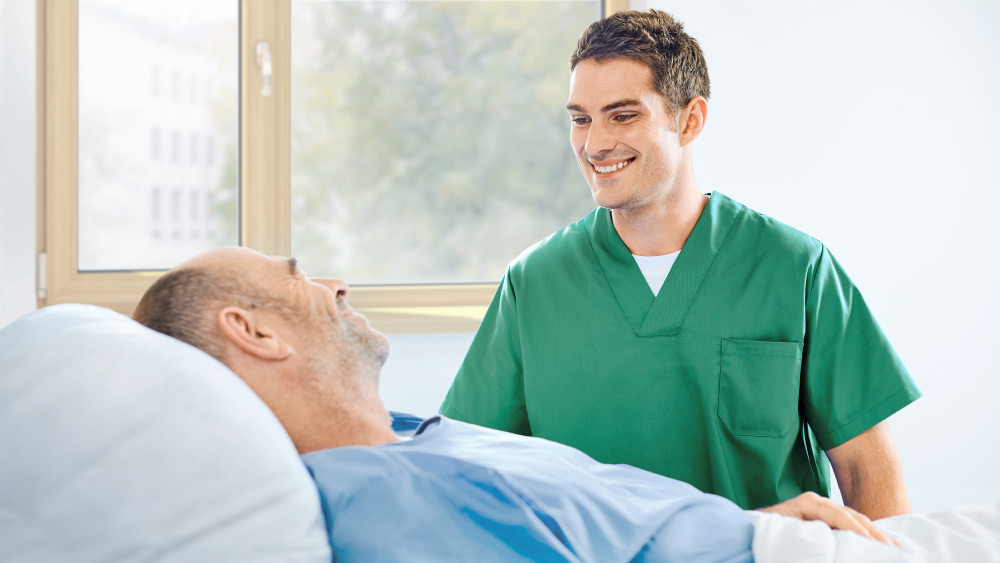 Enfermera hablando con un paciente a pie de cama