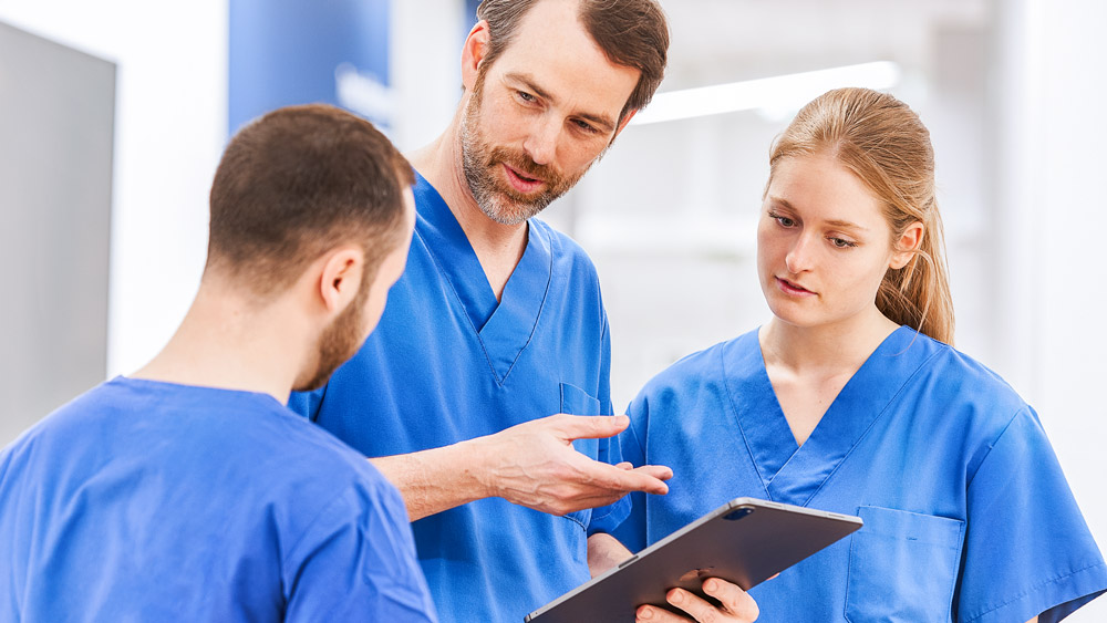 Tres médicos hablan sobre algo en una tableta