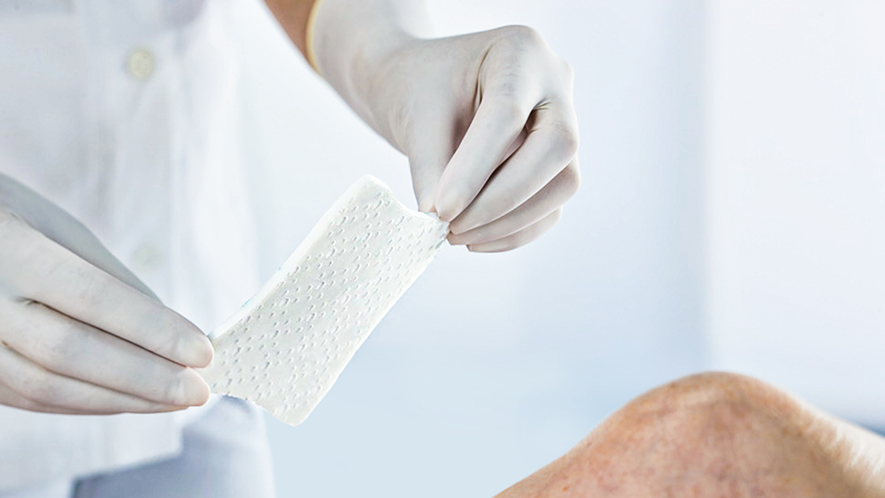 un parche se pega en una rodilla con dos manos con guantes