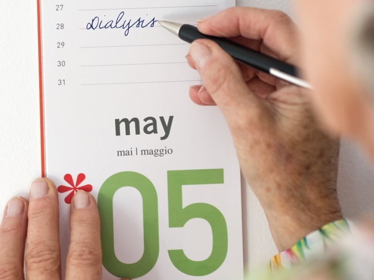 Una mano escribe la diálisis en un calendario para el 28 de mayo con un bolígrafo