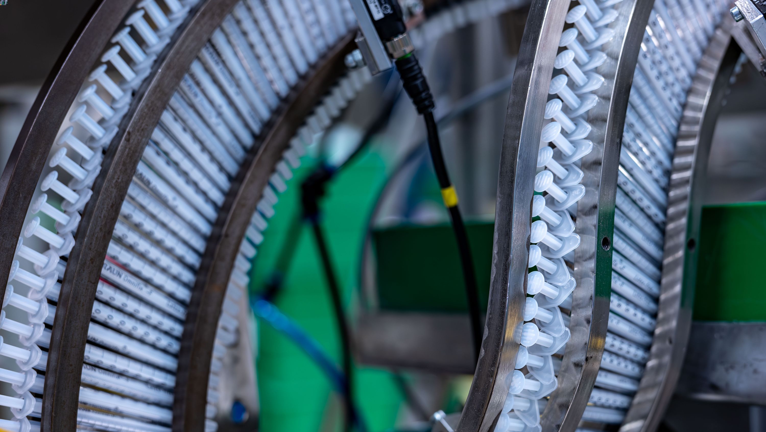 Muchas jeringas en fila en un entorno de producción. Simboliza nuestro análisis del ciclo de vida del producto para determinar el impacto medioambiental total de un producto, desde el suministro de las materias primas hasta su eliminación. 